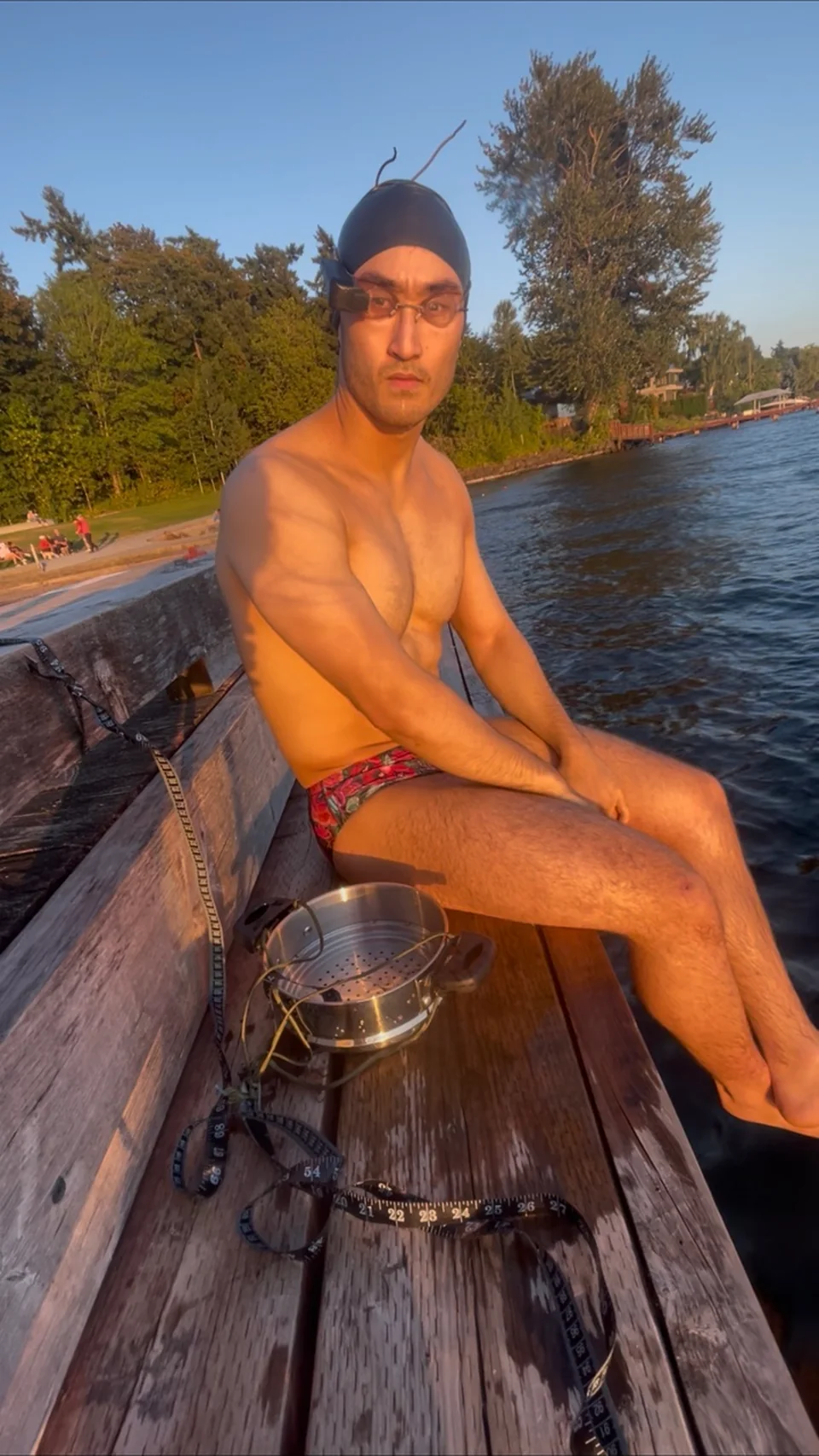 Sam in a swimsuit wearing the movie-goggle prototype beside a lake before a swim test